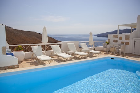 Una piscina al aire libre, sillones reclinables de piscina