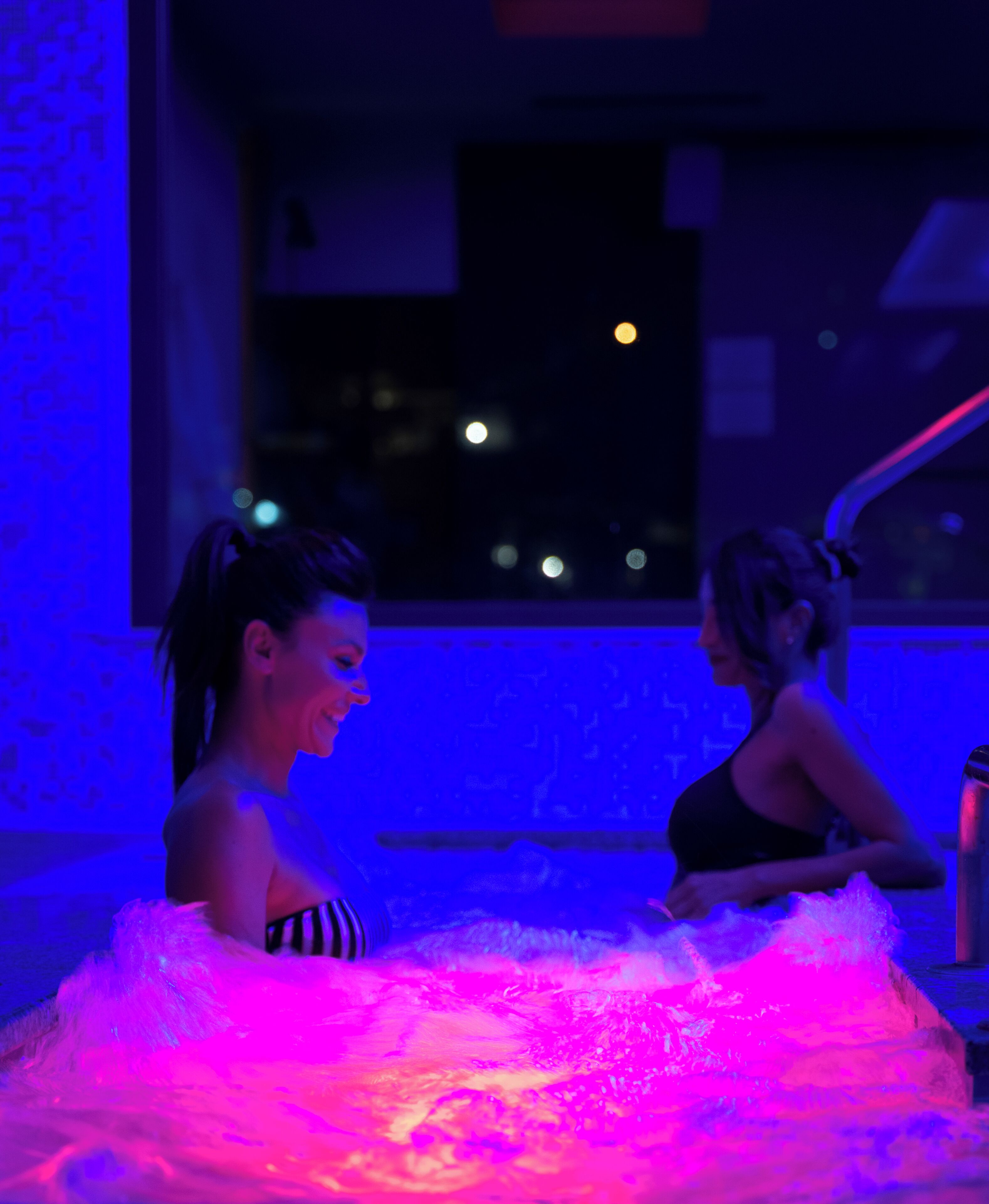 Dos personas en una habitación con un objeto grande, mullido, iluminado en rosa y azul.