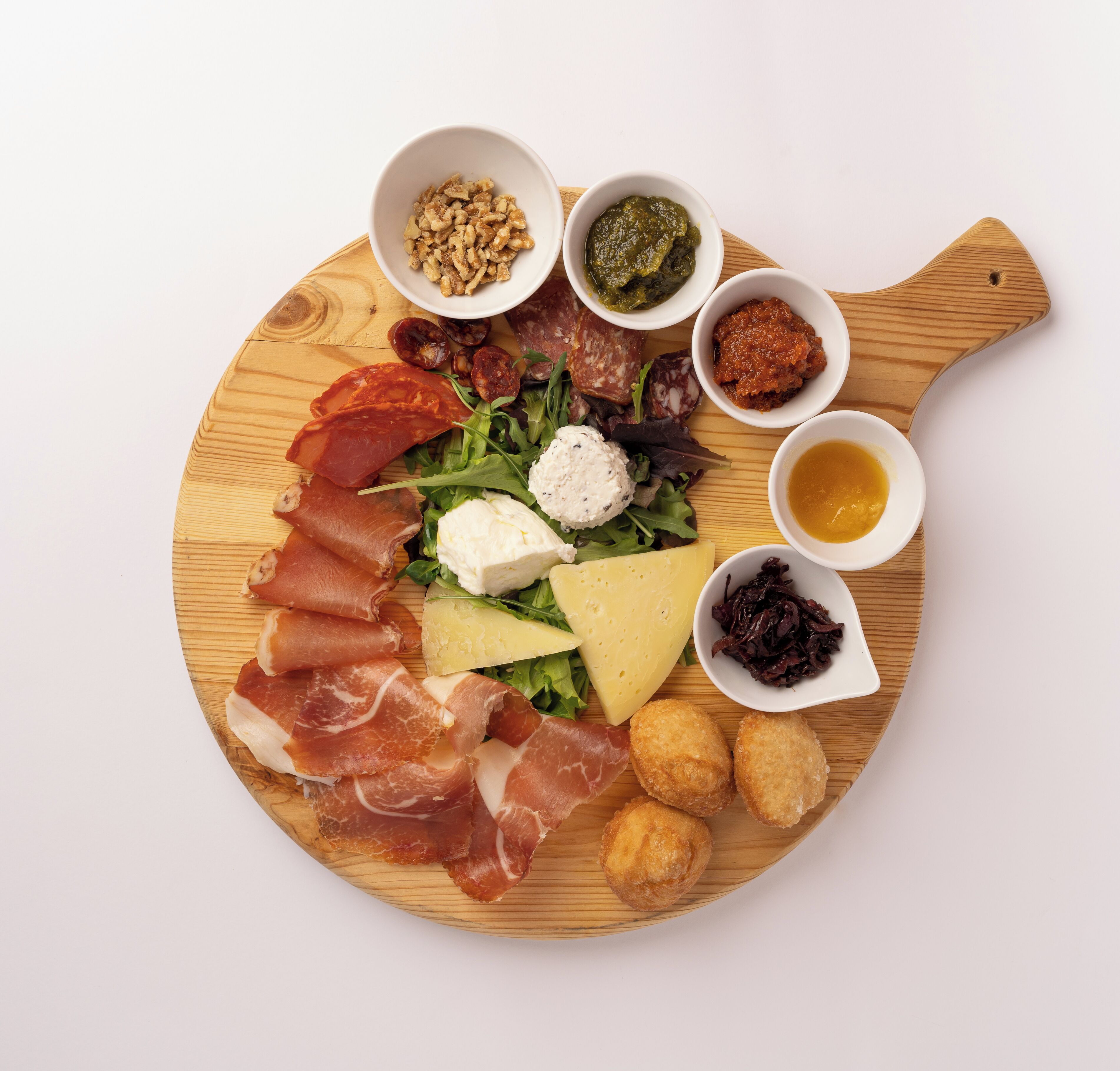 Ein Holzbruch mit verschiedenen Speisen, darunter Fleisch, Käse und Soßen.