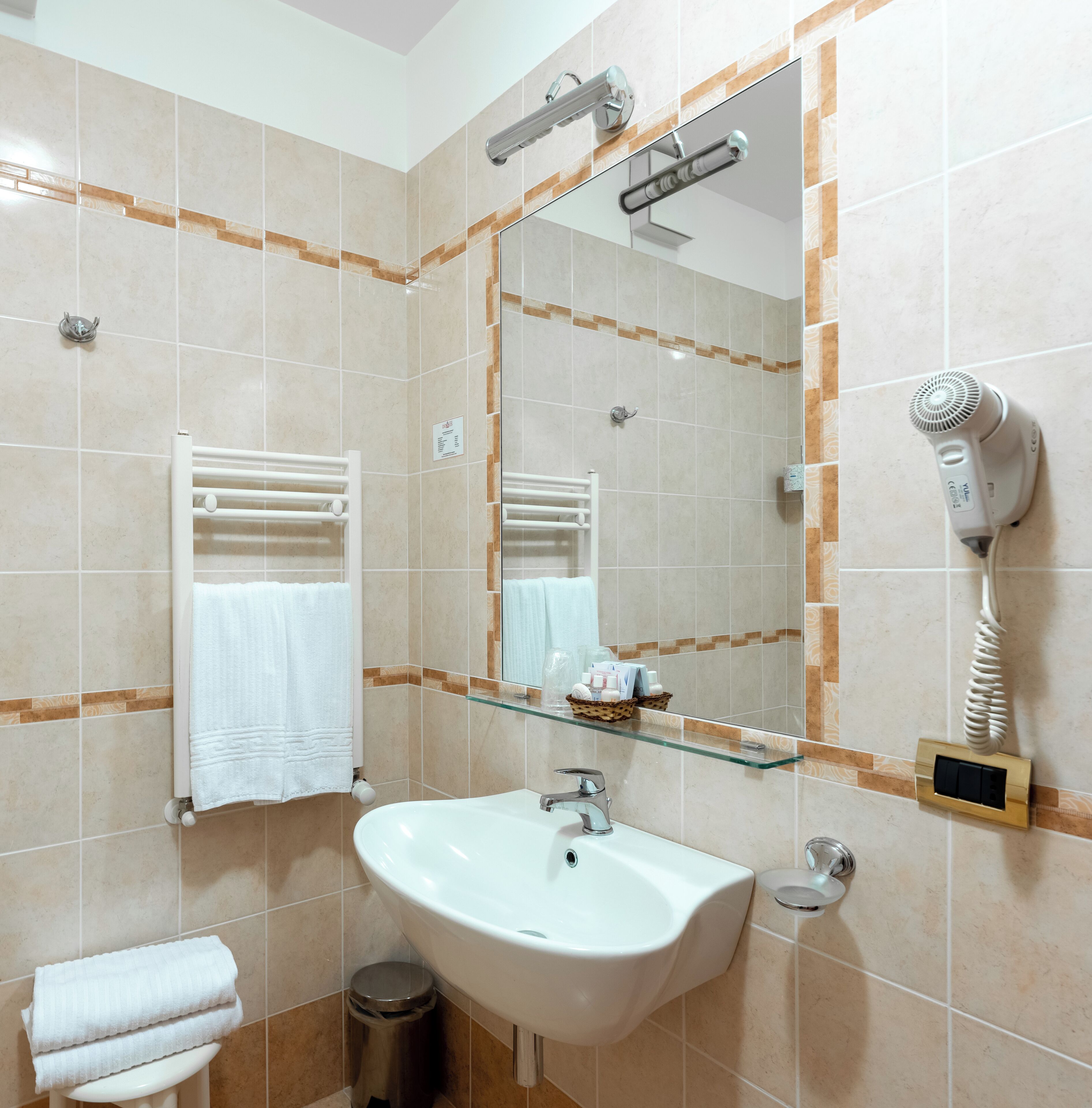 A bathroom with a sink, mirror, towel rack, and a hairdryer.