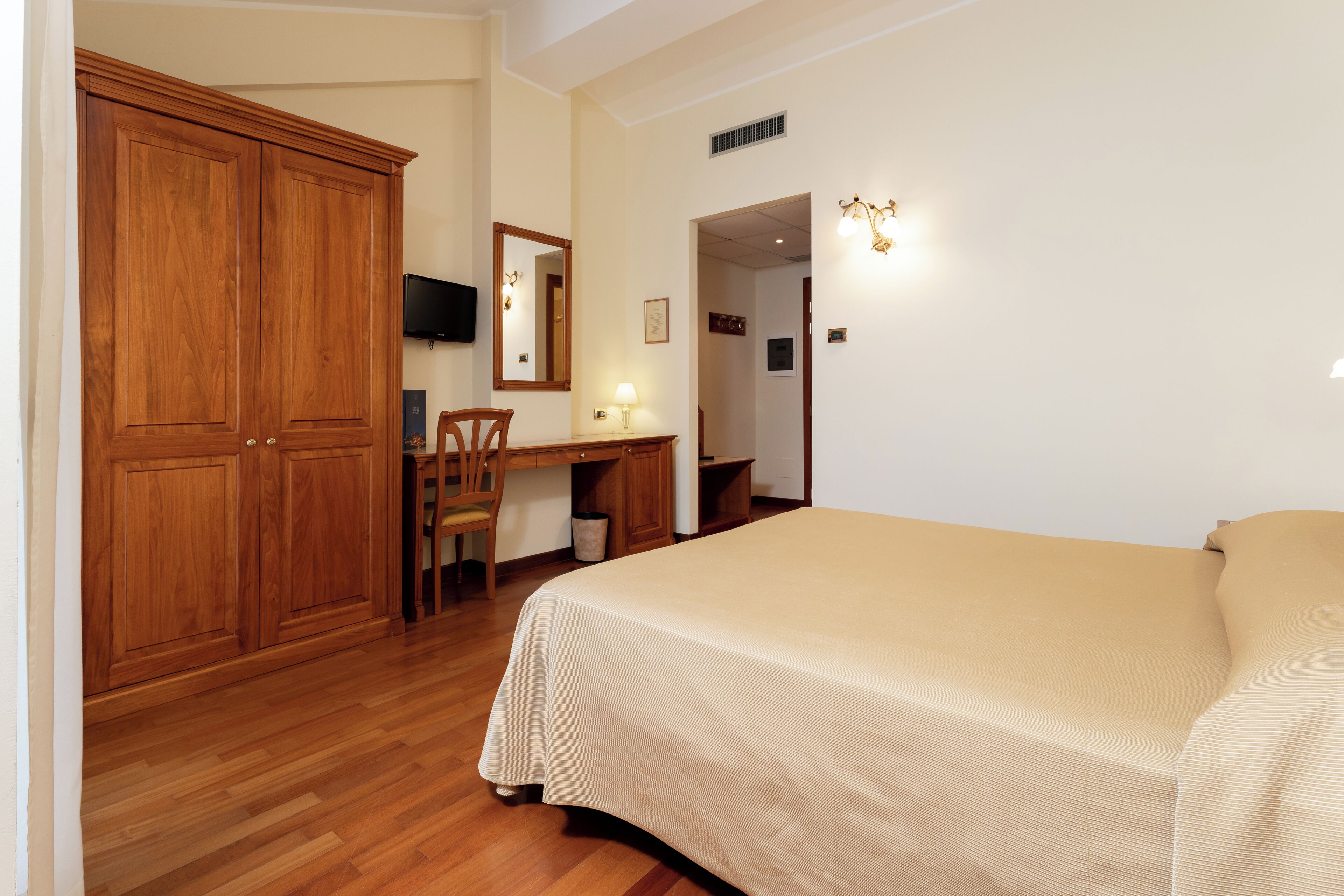 Un dormitorio con una cama grande, un armario de madera, un escritorio y una silla.