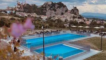 Una piscina al aire libre de temporada, sombrillas