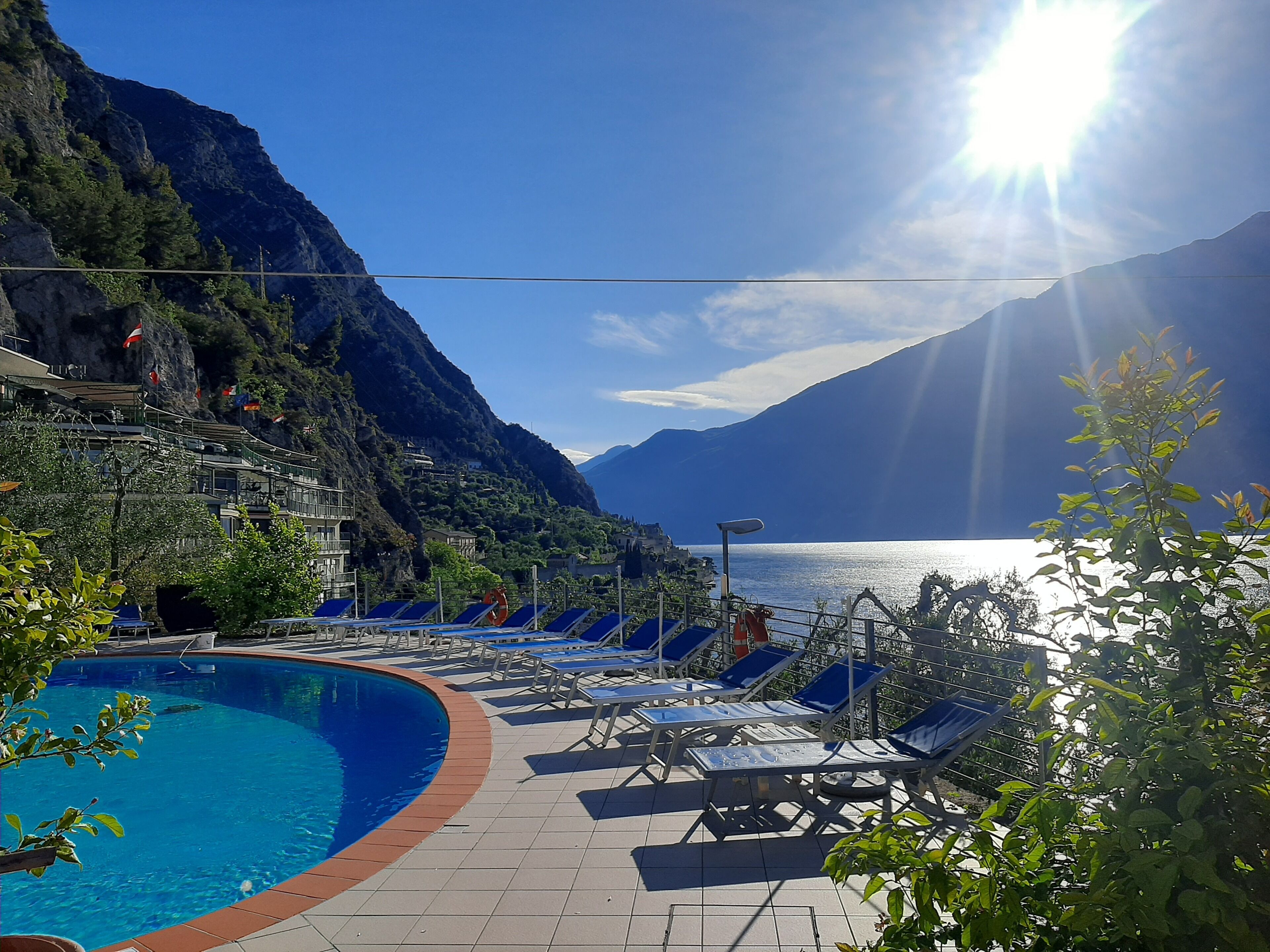 Area piscina con sedie a sdraio e vista su un lago e montagne.