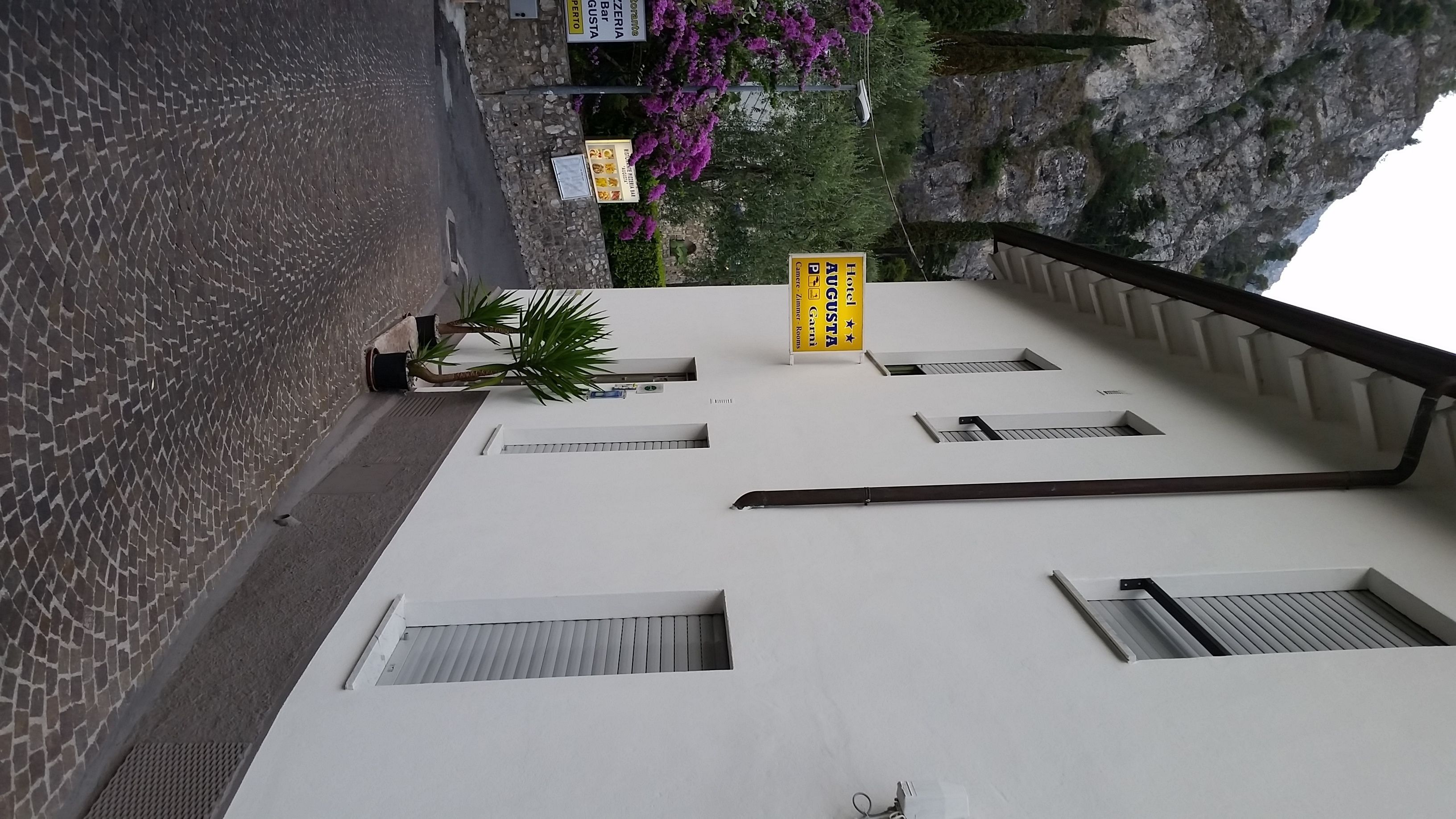 A hotel with a white facade, multiple windows, and a balcony railing.