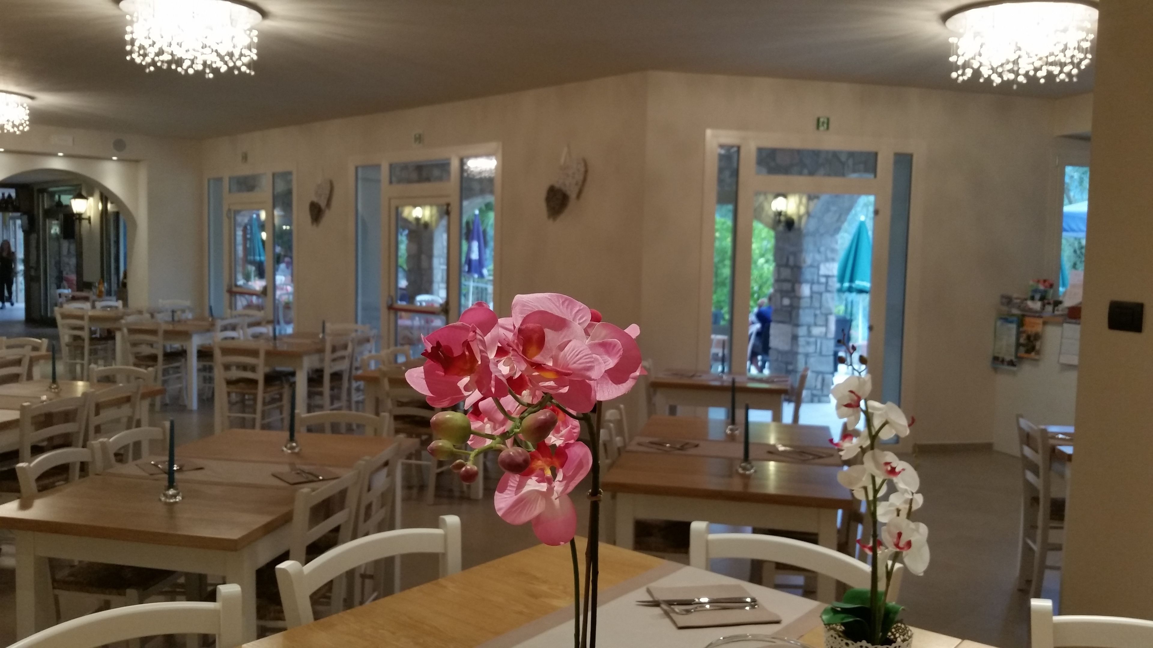 Un restaurante con mesas y sillas de madera, ventanas amplias y decoración mural.