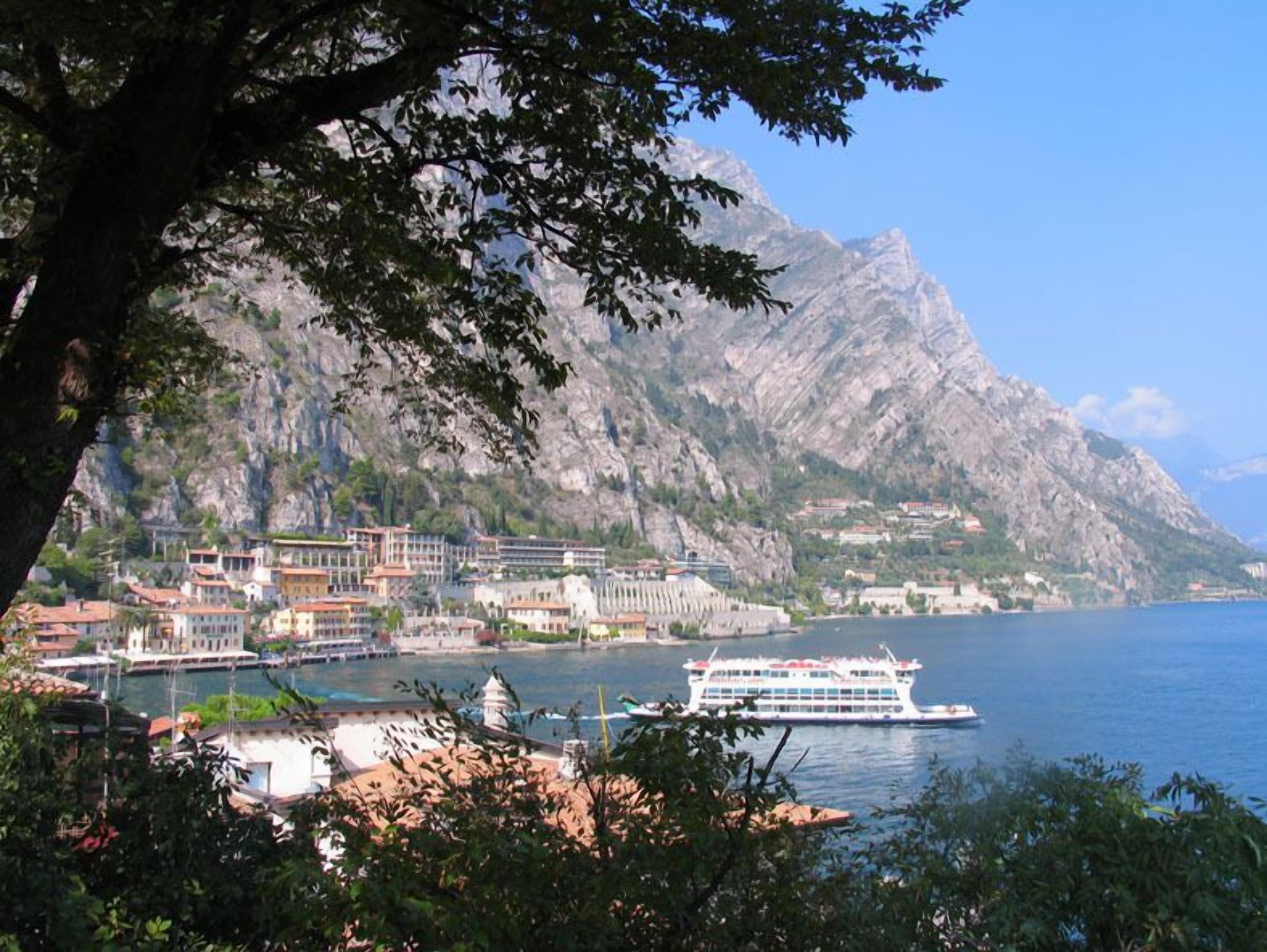 A coastal town with a large cruise ship docked at the harbor, surrounded by rocky mountains and lush greenery.