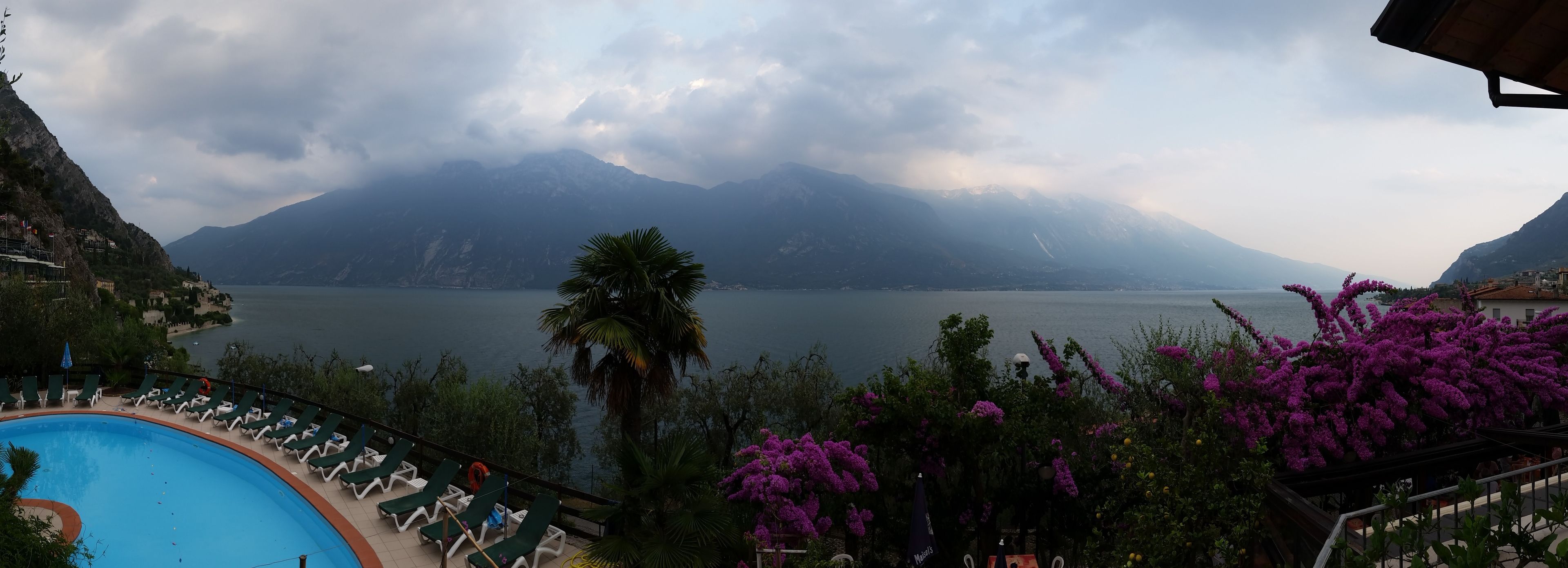 Ein Poolbereich mit Liegestühlen und Blick auf einen See und Berge.