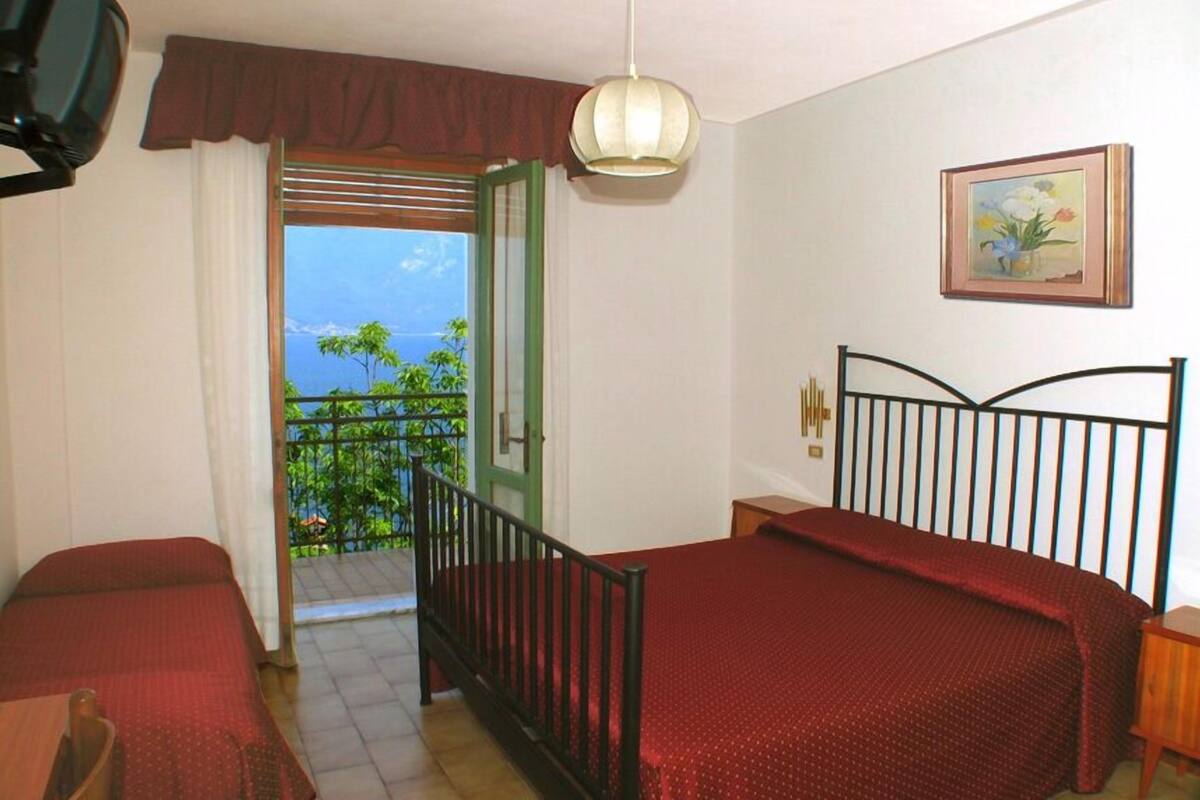 Habitación de hotel con dos camas, un balcón, vista al océano y un cuadro en la pared.