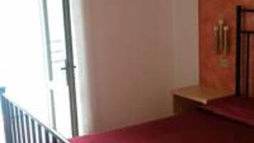 Una habitación con alfombra roja, una pequeña mesa de madera y una barandilla de metal negro.