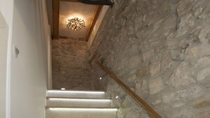 Eine Treppe mit hölzernem Geländer, weißen Stufen und einer Steinmauer.