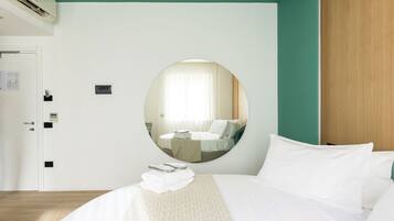 Habitación de hotel con cama, espejo redondo, puerta y aire acondicionado instalado en la pared.