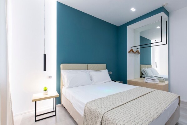 Un dormitorio moderno con cama, mesita de noche y espejo.