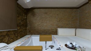 A modern bathroom with a bathtub, a bench, and a tray with teapots and cups. - Hotel Plana (Caserta)