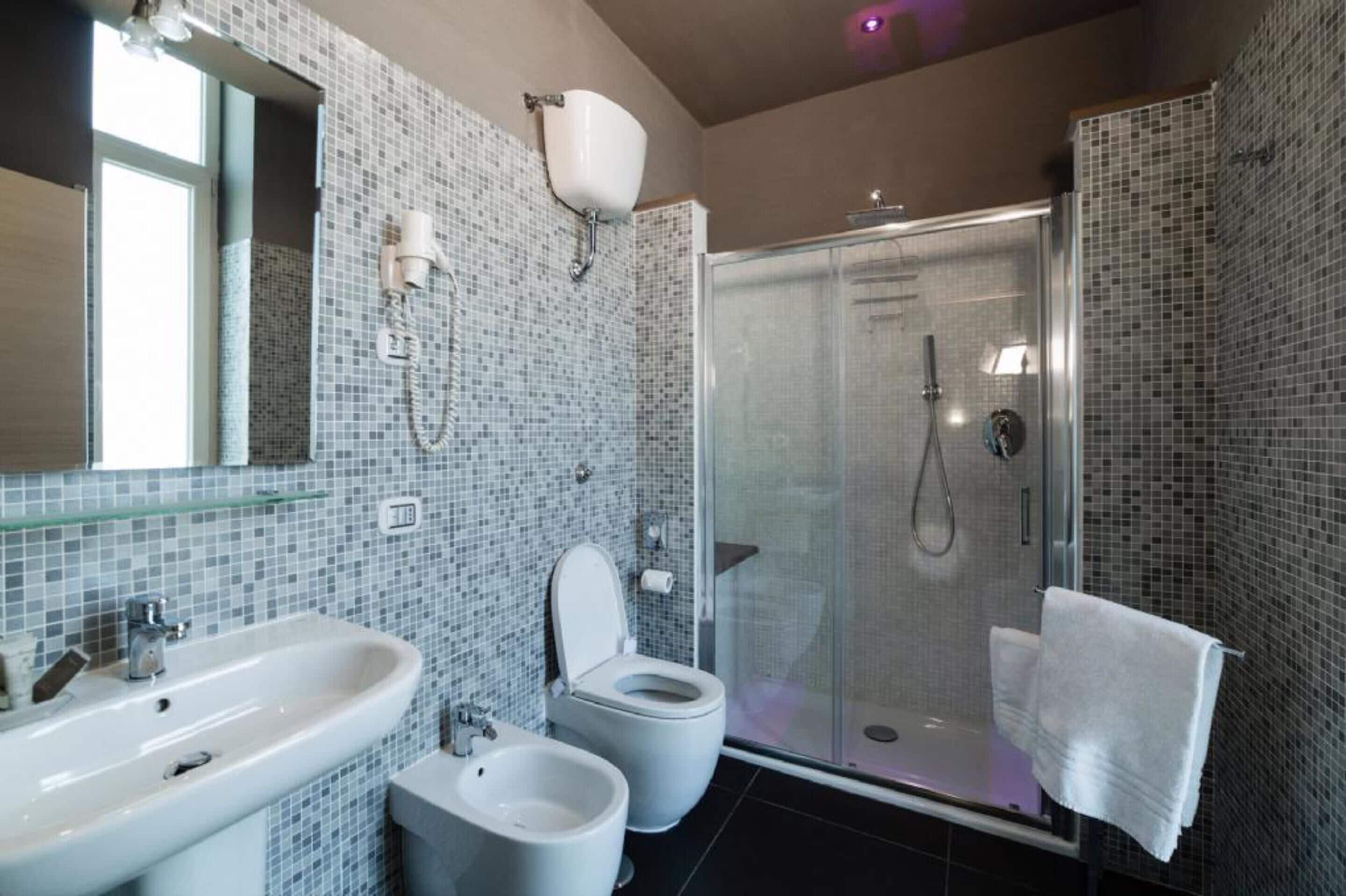 Un baño moderno con cabina de ducha de vidrio, un bidé, un inodoro y un lavabo.