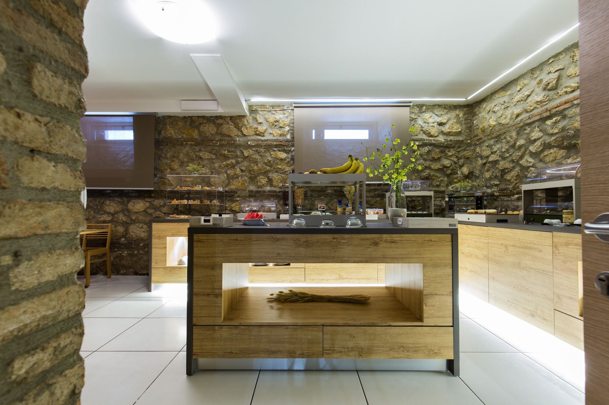 Una cocina moderna con un fondo de pared de piedra, una isla central con base de madera y un horno empotrado.