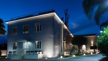 A modern two-story building with a flat roof, large windows, and a well-lit entrance.