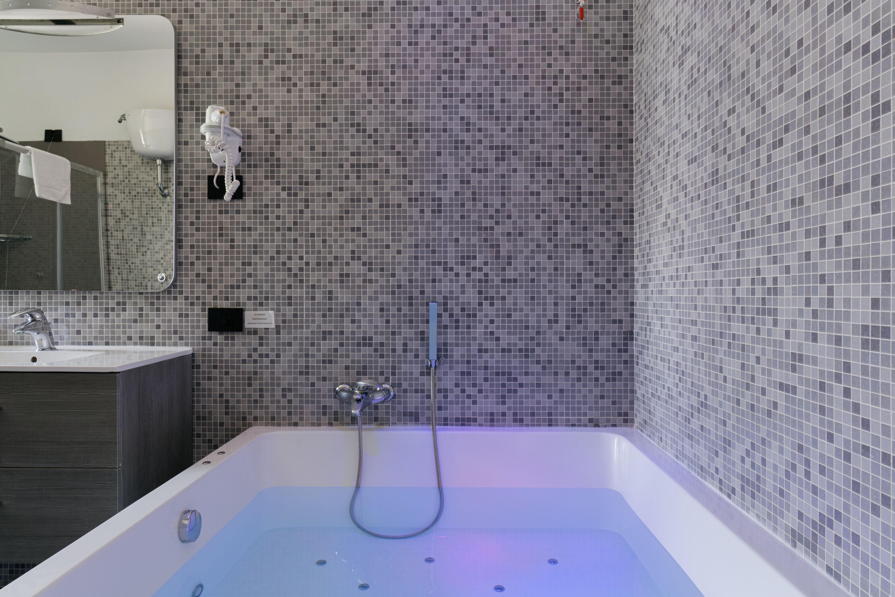 Un bagno moderno con una vasca da bagno ampia, uno specchio, un lavandino e un water.