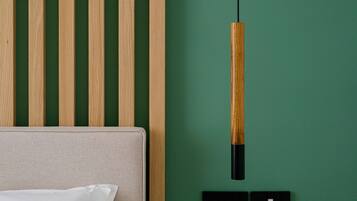 Una habitación con pared verde, panel de pared de listones de madera, sofá beige y una lámpara colgante.