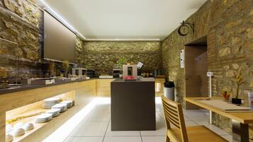 A modern kitchen with stone walls, a central island, and a dining area with a wooden bench.