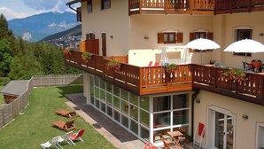 A two-story building with a balcony, outdoor seating area, and a view of mountains. - Seggiovia (Folgaria)