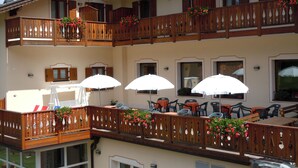 A multi-story building with balconies, outdoor seating, and flower baskets. - Seggiovia (Folgaria)