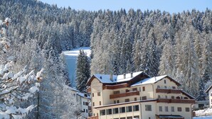 A multi-story hotel with a snow-covered landscape and forest in the background. - Seggiovia (Folgaria)