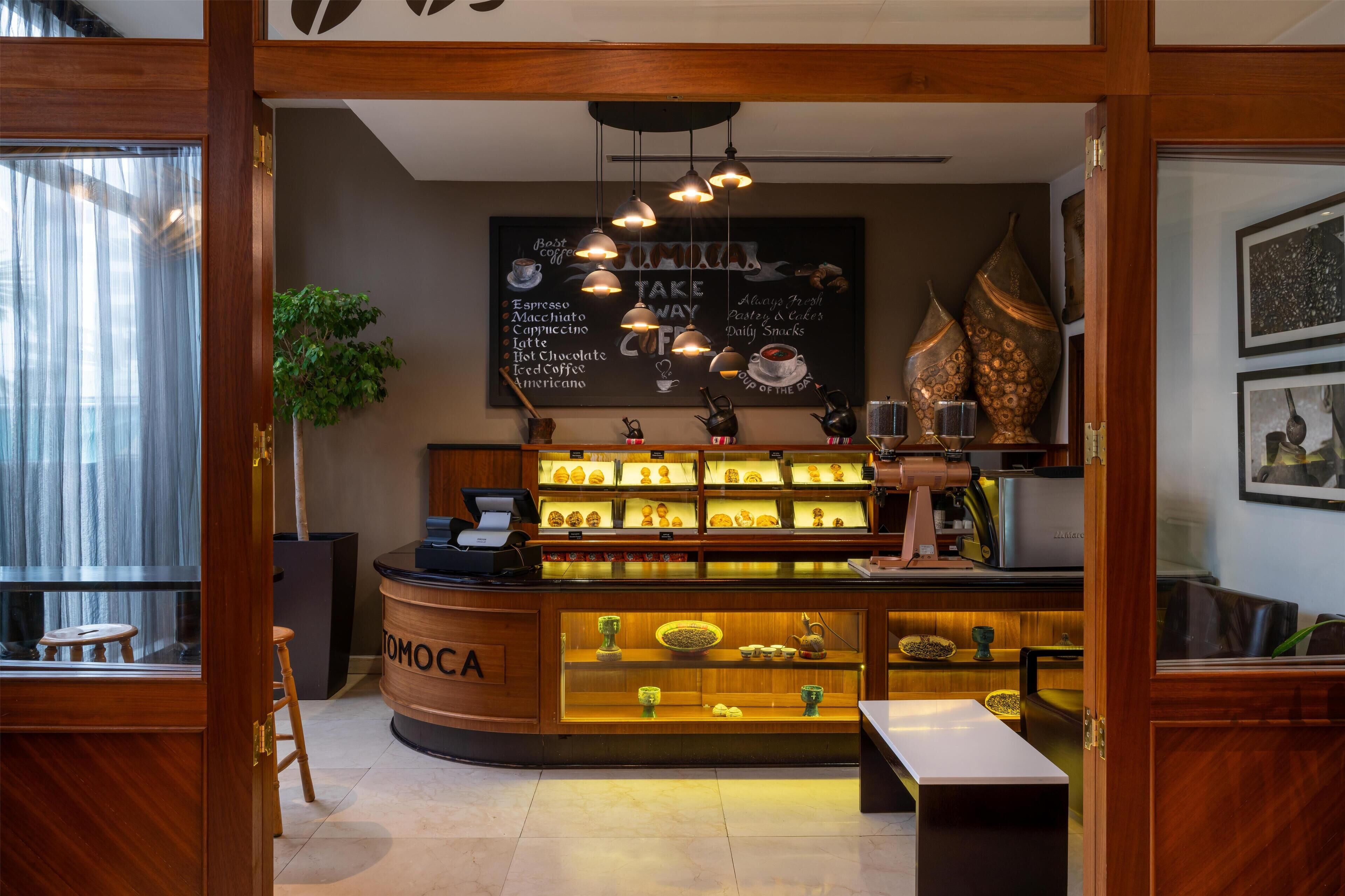 A coffee shop interior with a counter displaying various coffee options and a menu board above.