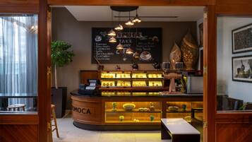 Interior de uma cafeteria, com um balcão exibindo diversas opções de café e um quadro de cardápio acima.