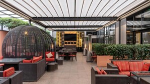 An outdoor seating area with wicker furniture, a large woven structure, and a wall of liquor bottles.