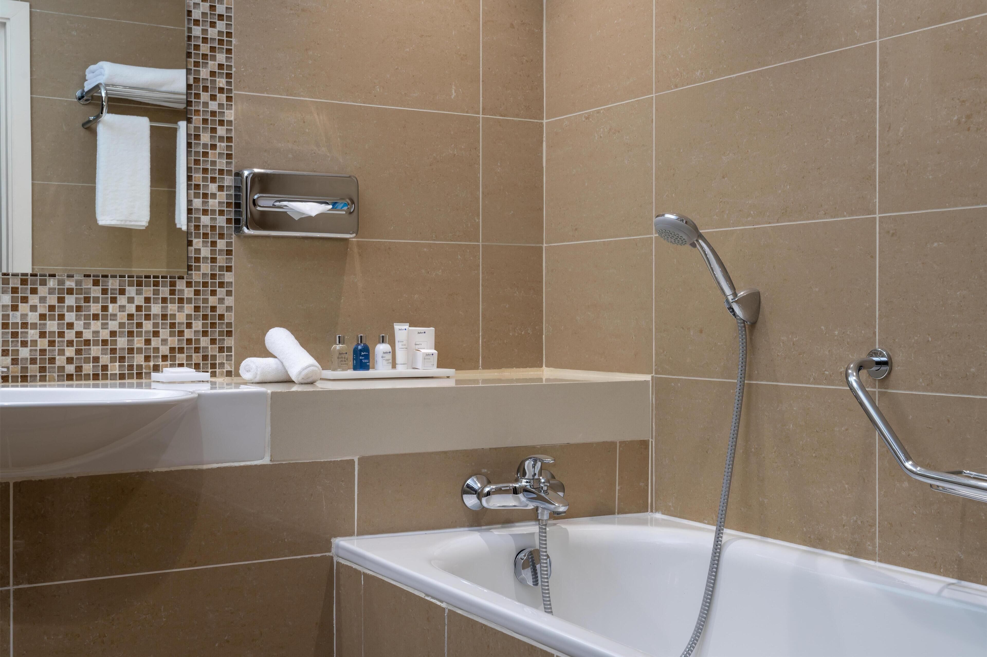 Un baño moderno con bañera, lavamanos, espejo y toallero.