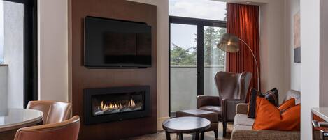 Una sala de estar moderna con chimenea, asientos cómodos y un ventanal grande.