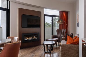 A modern living room with a fireplace, comfortable seating, and a large window.