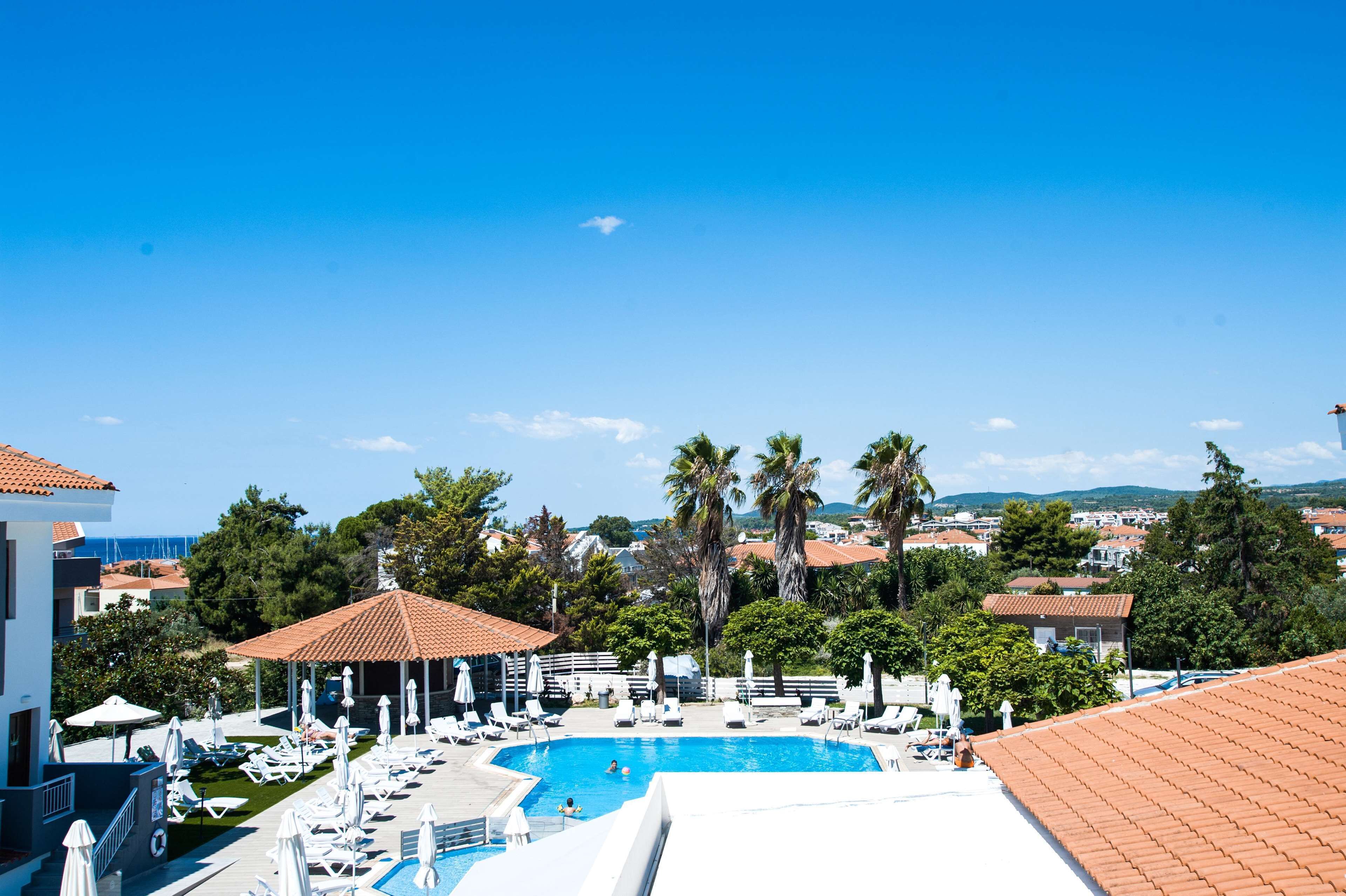 A resort with a swimming pool, sun loungers, and a view of the surrounding town.