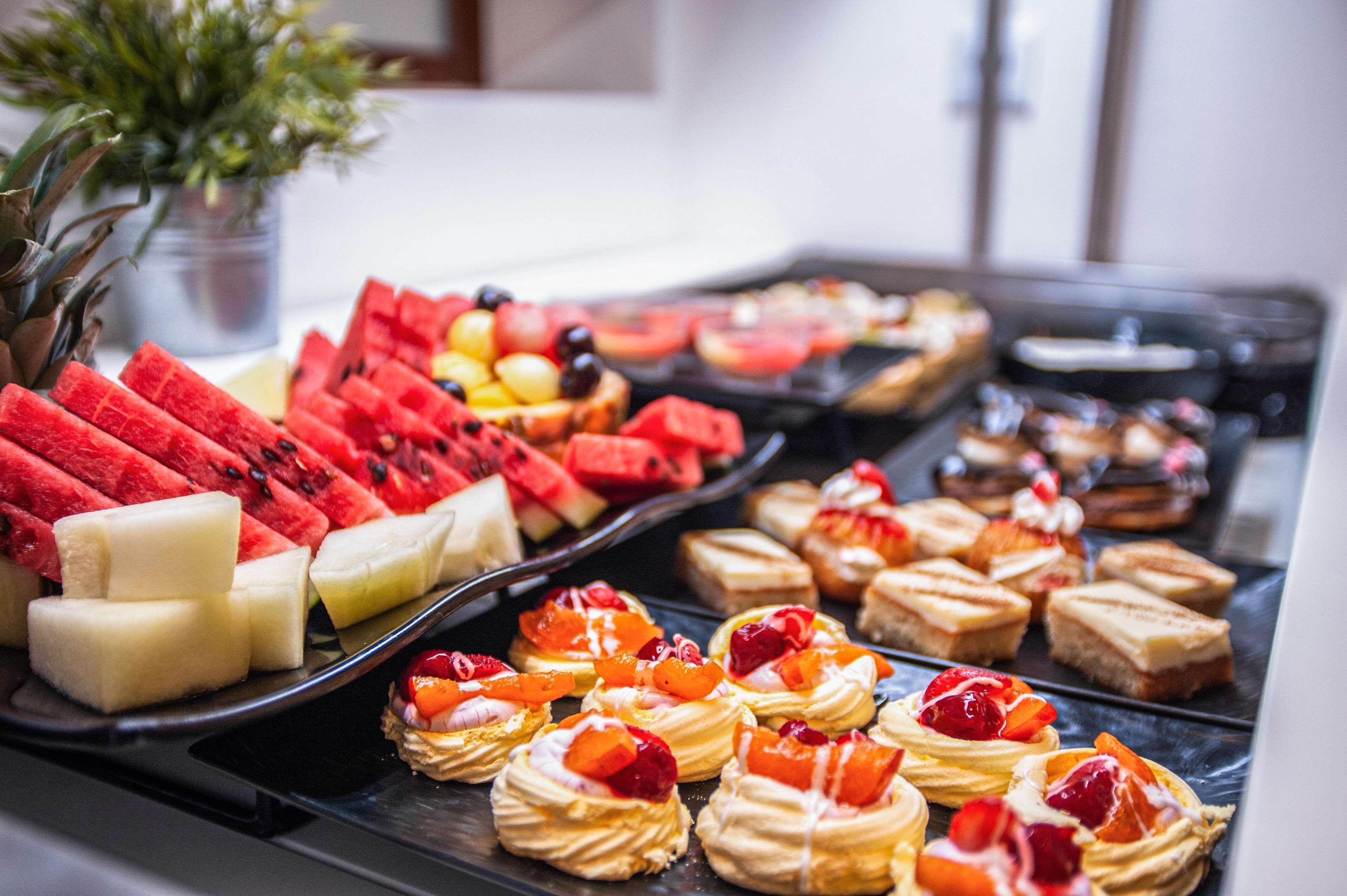 Un bufé con diversas frutas y postres.