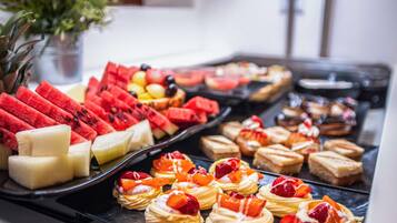 Un bufé con diversas frutas y postres.