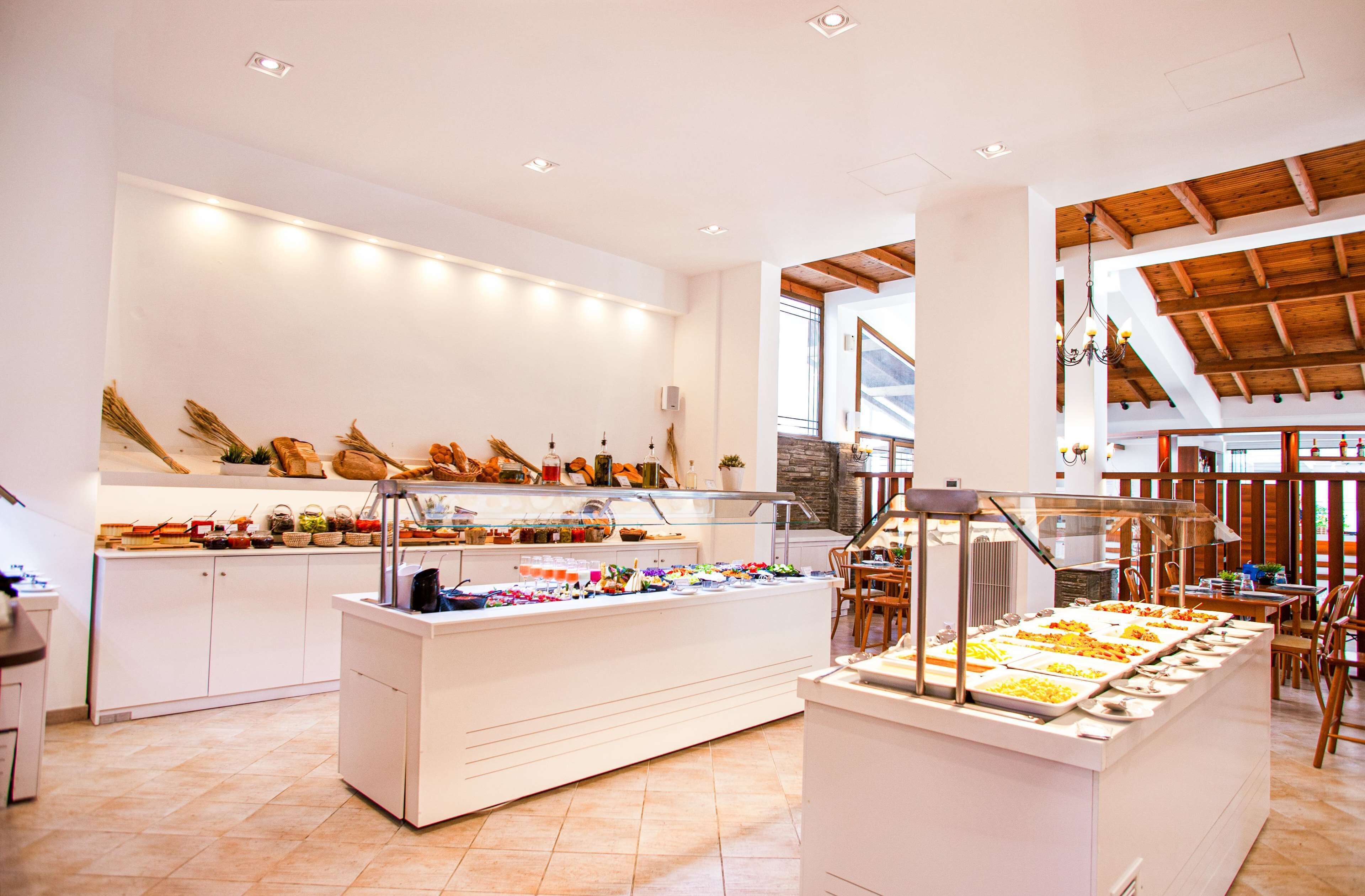 A buffet area with multiple food stations, a seating area with tables and chairs, and a kitchen in the background.