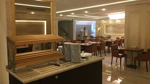 Un restaurant moderne doté d’un espace buffet, de plusieurs tables et d’un escalier menant à un niveau supérieur.