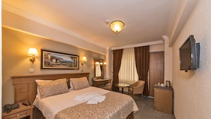 Une chambre d’hôtel comprenant un lit, une table de chevet, une lampe, un tableau, un miroir, un bureau, une chaise et un téléviseur.