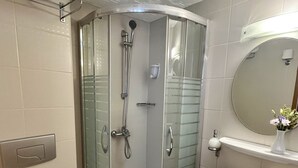 A bathroom with a glass-enclosed shower, a toilet, and a sink with a mirror above it. - Yavuz Otel (Istanbul)