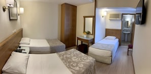 A hotel room with two single beds, a wooden wardrobe, a small table with a vase, and a bathroom visible through an open door. - Yavuz Otel (Istanbul)