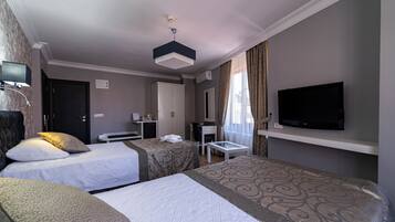 A hotel room with two beds, a desk, a television, and an air conditioning unit.