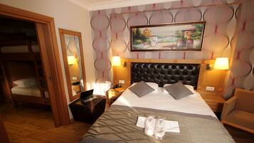 Hotelkamer met een groot bed, hoofdbord, twee bedlampen, een schilderij aan de muur, een houten garderobe en een spiegel.