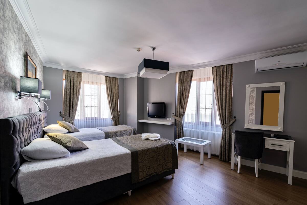 Habitación de hotel con dos camas, televisión, escritorio y silla.