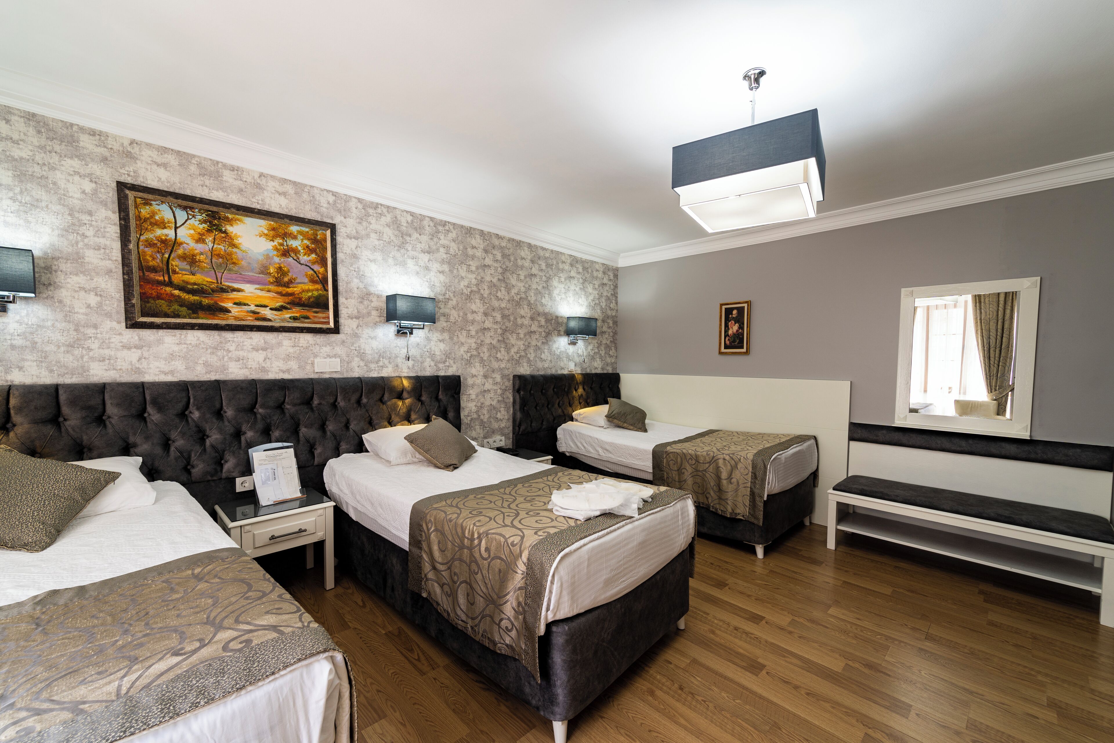 Habitación de hotel con dos camas, un cuadro grande en la pared y un banco.
