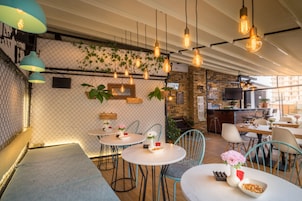 Un restaurante acogedor con mesas redondas, luces colgantes y una pared de ladrillo.