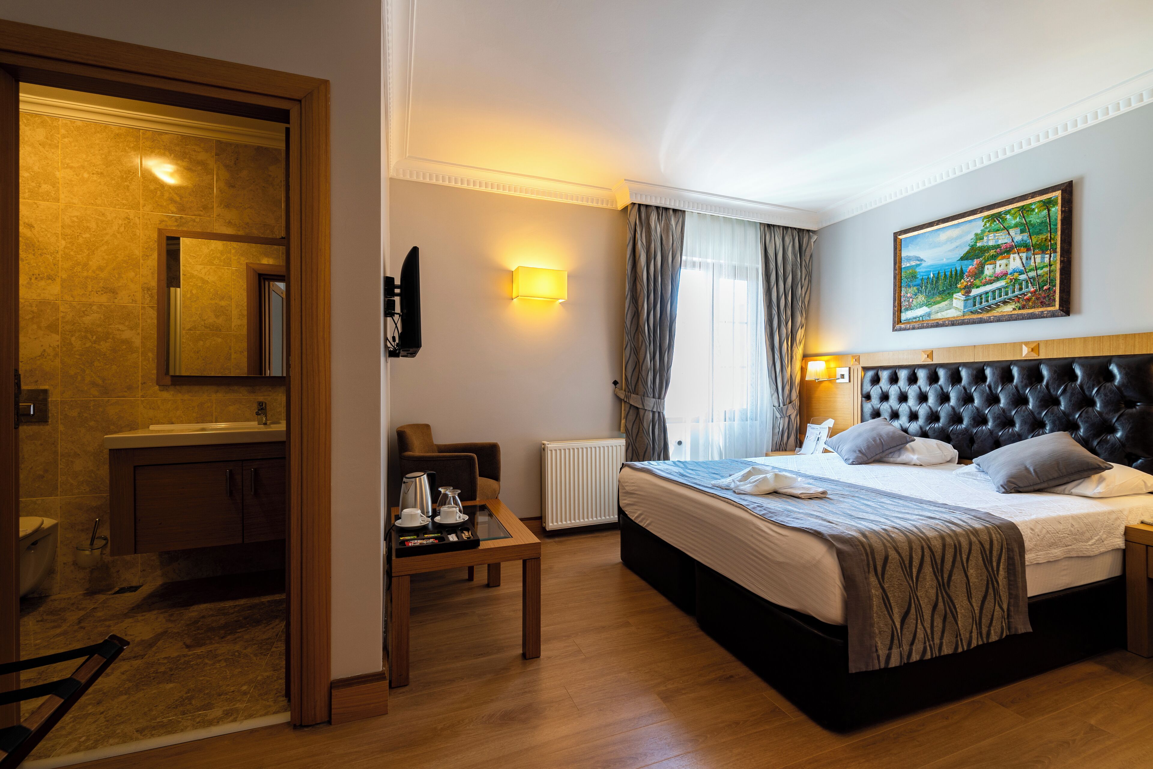 Una habitación de hotel con cama, mesita de noche, lámpara y un cuadro en la pared.