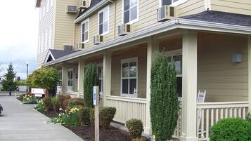 A multi-story residential building with a covered front porch and small front yard.