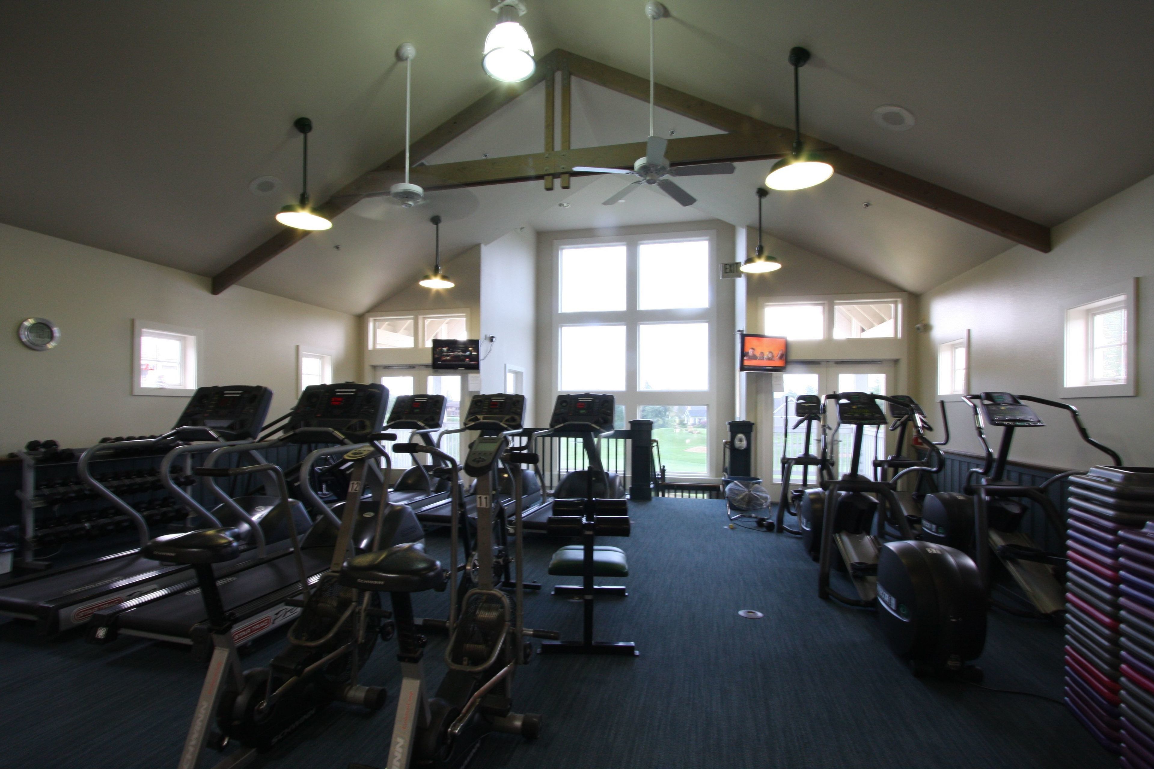 Ein Fitnessstudio mit Laufbändern, Crosstrainern und stationären Fahrrädern.