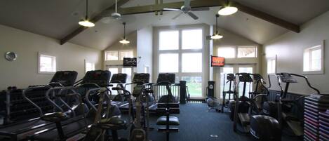 Ein Fitnessstudio mit Laufbändern, Crosstrainern und stationären Fahrrädern.