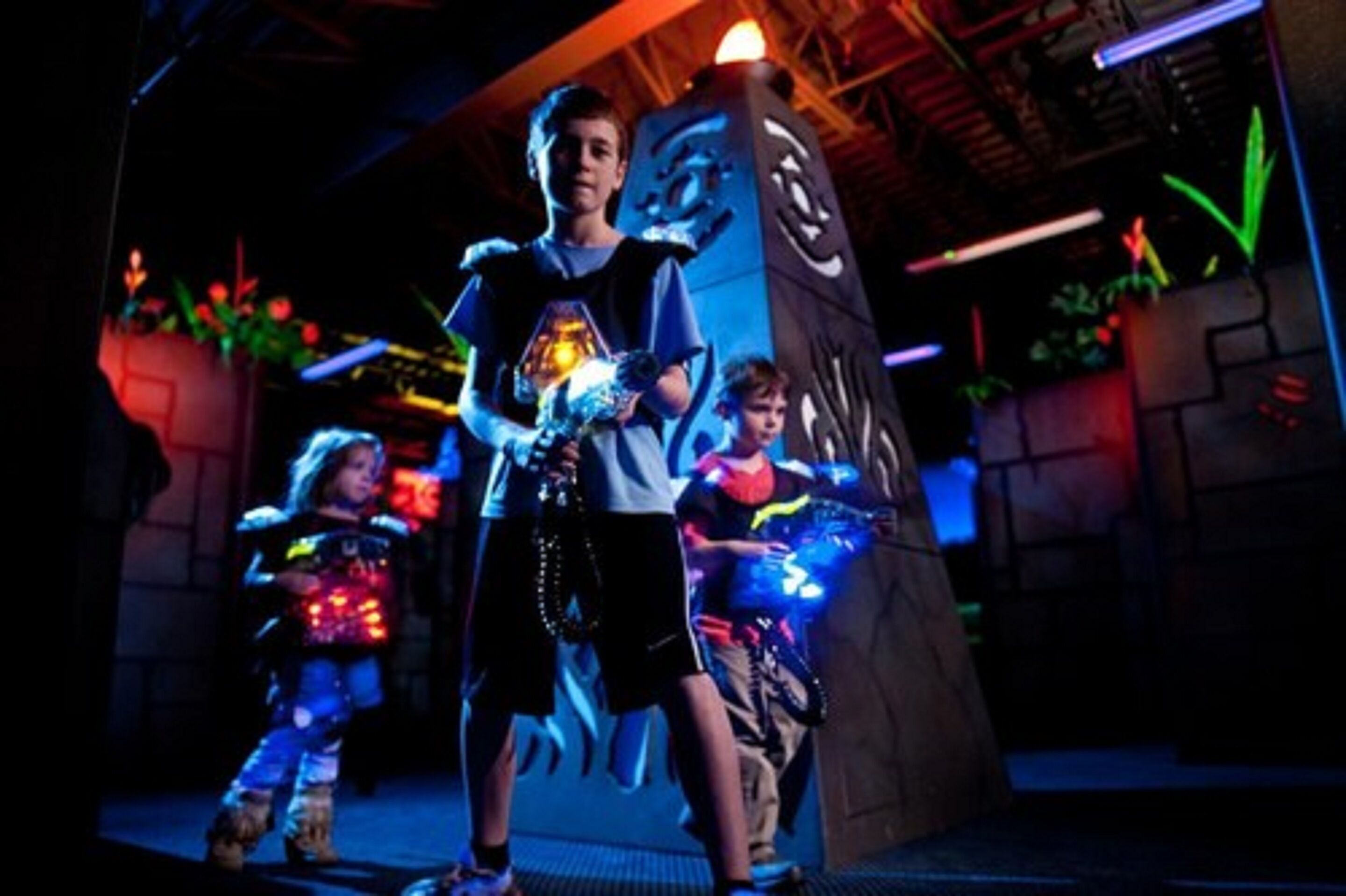 A child in a costume holding a glowing object, standing in front of a large, illuminated structure with a dragon design.
